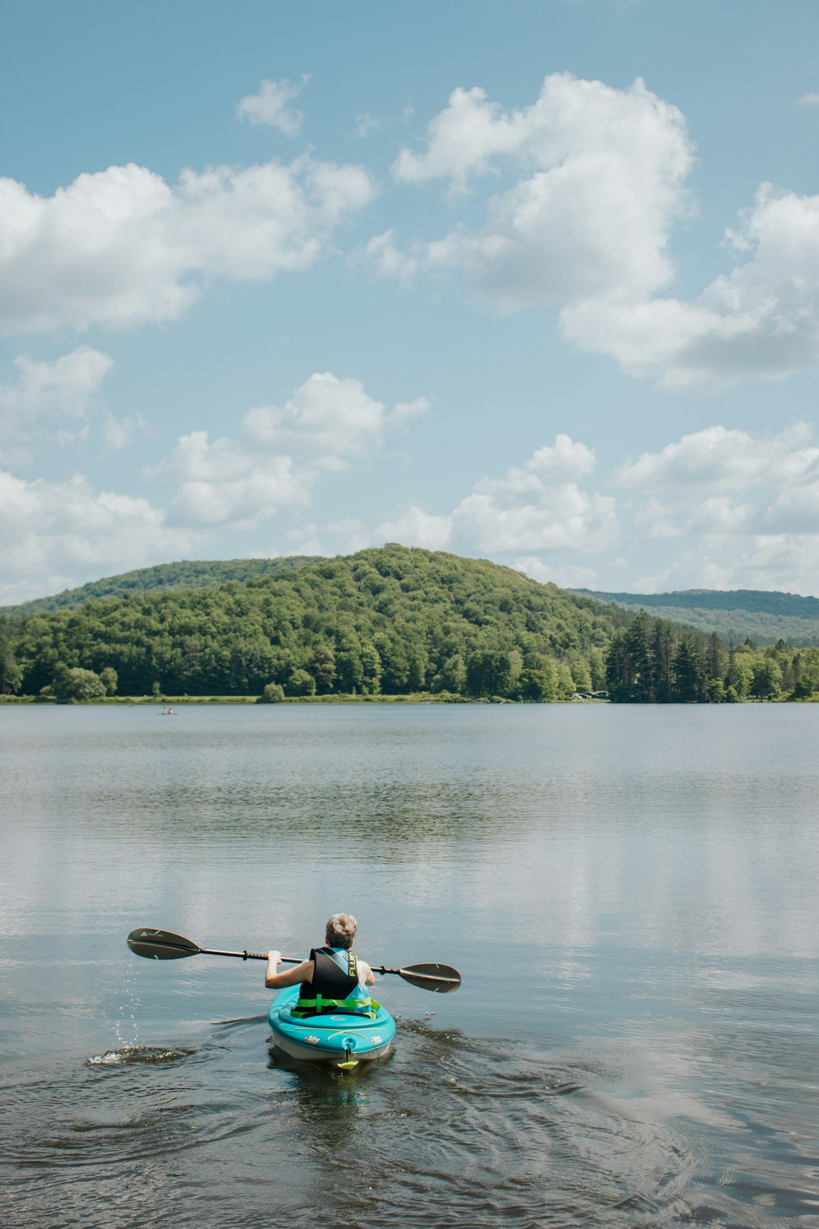 A lone kayaker paddling across a calm lake